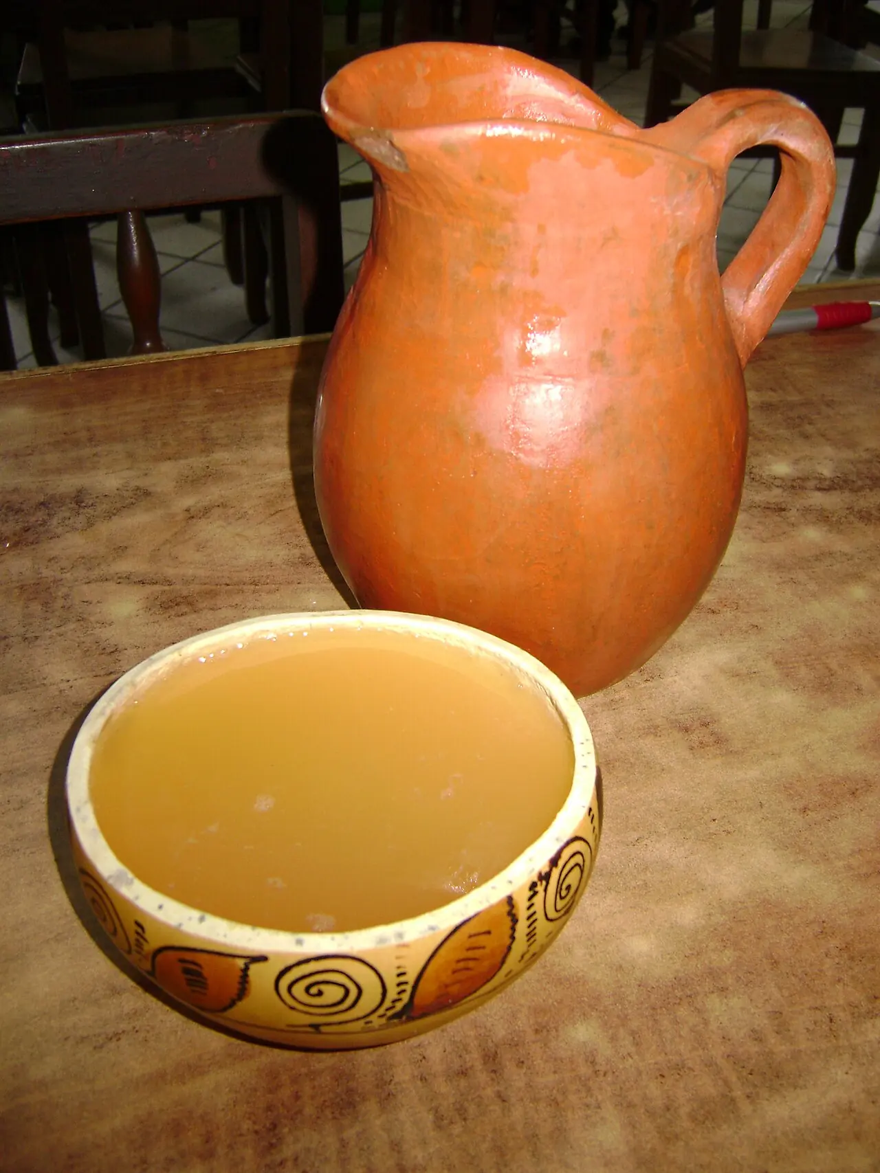 Clarito servido en un poto de calabaza junto a una jarra de barro