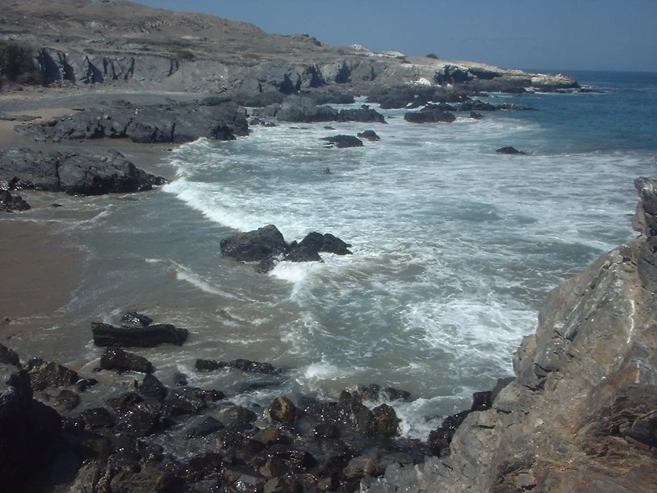 Acantilados de roca oscura y olas rompiendo en la península de Illescas