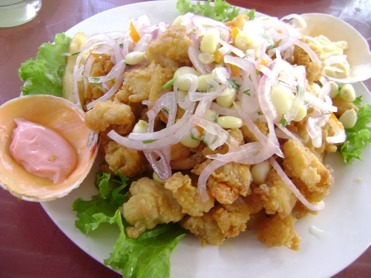Jalea mixta: pescado y mariscos fritos con sarsa criolla, choclo, lechuga y cremas