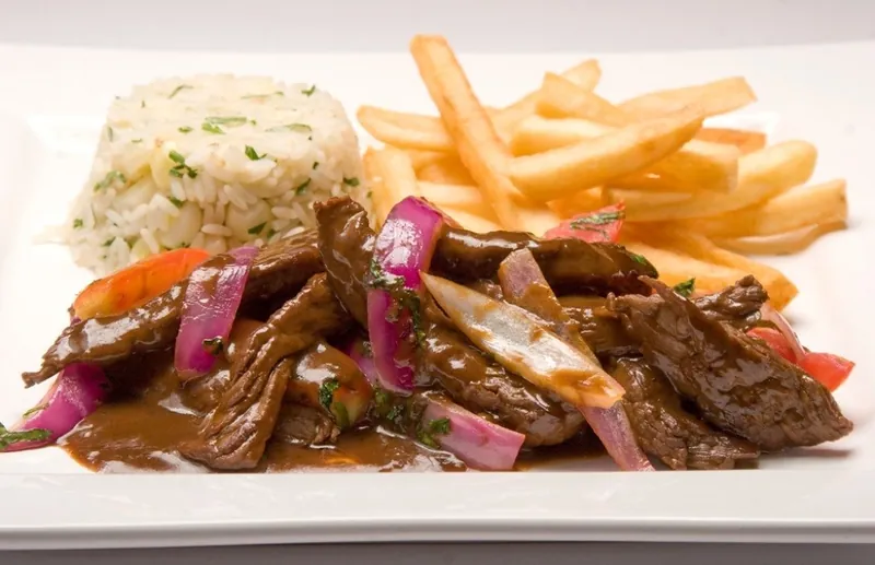 Lomo saltado con cebolla roja, tomate, papas fritas y arroz